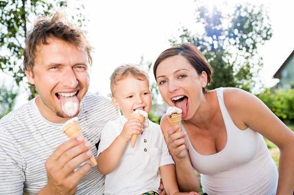 Young parents with their little son eating ice cream from a soft serve ice cream machine
